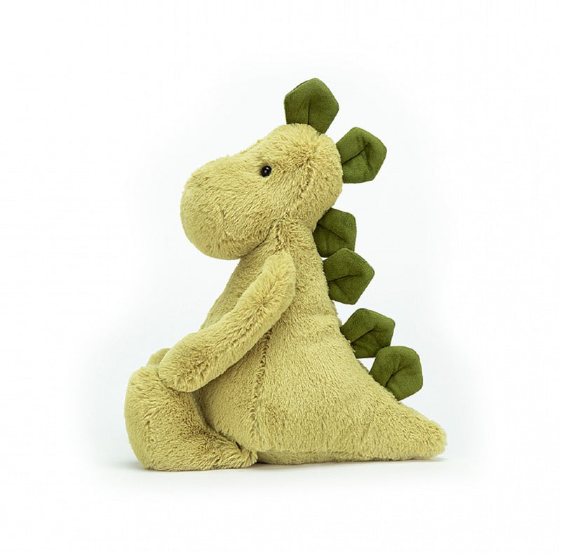 Peluche dinosaure vert de profil devant un fond blanc 