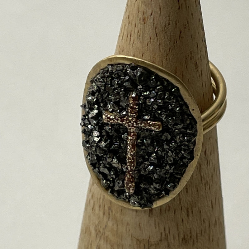 Bague Lakstone Croix Pyrite sur un cône en bois et devant un fond blanc 