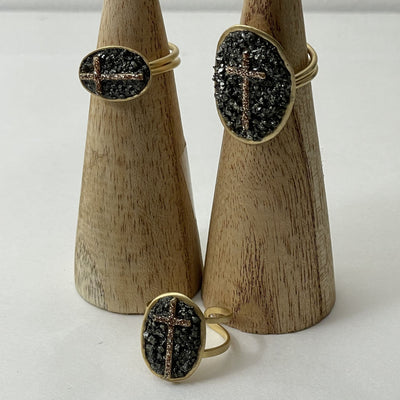 Bague Lakstone Croix Pyrite sur des cônes en bois devant un fond blanc 