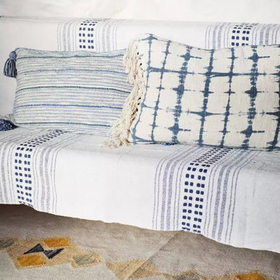 Plaid rayé bleu sur un canapé avec des coussins bleus 