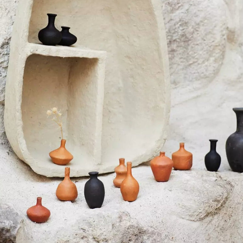 Vase amphore terre cuite terracotta et noir avec plusieurs vases en terre cuite sur des pierres
