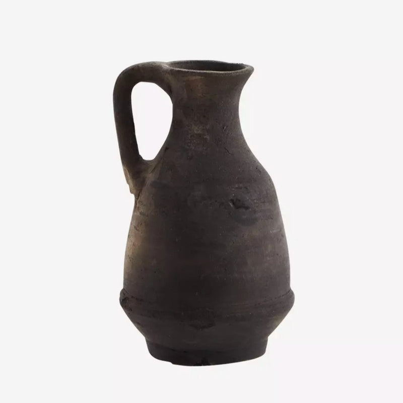 Vase en terre cuite noir devant un fond blanc 