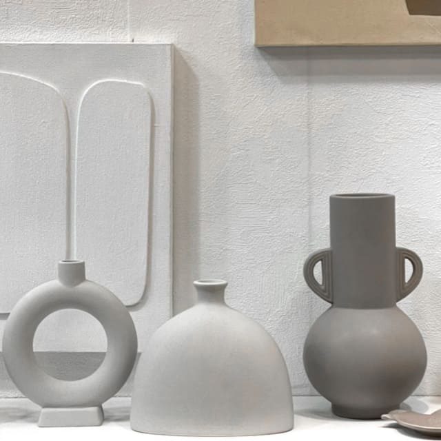 Vase en céramique gris devant un fond gris et des objets gris