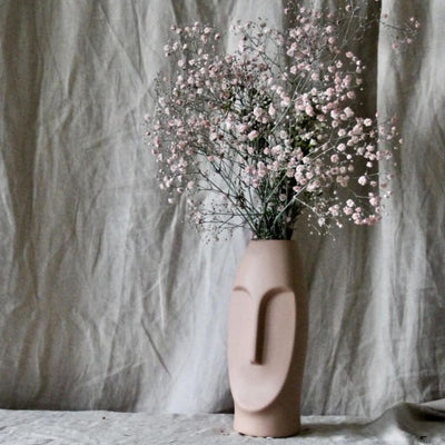 Vase visage rose avec des fleurs roses à l'intérieur 