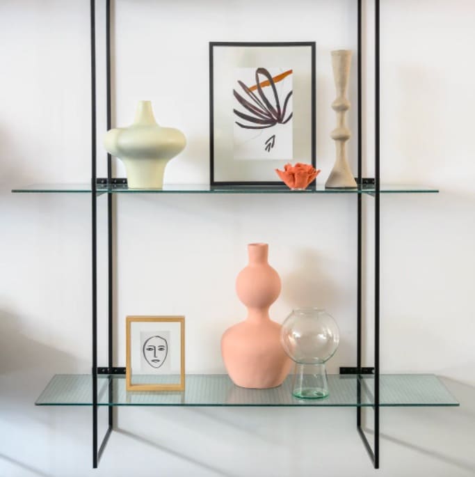 Cadres photos et vases entreposés sur une étagère en verre à deux étages