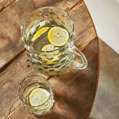 Carafe transparente à points sur une table en bois avec de la citronnade à l'intérieur