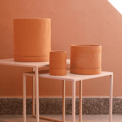 Pots en terre cuite posés sur des tables en métal rose
