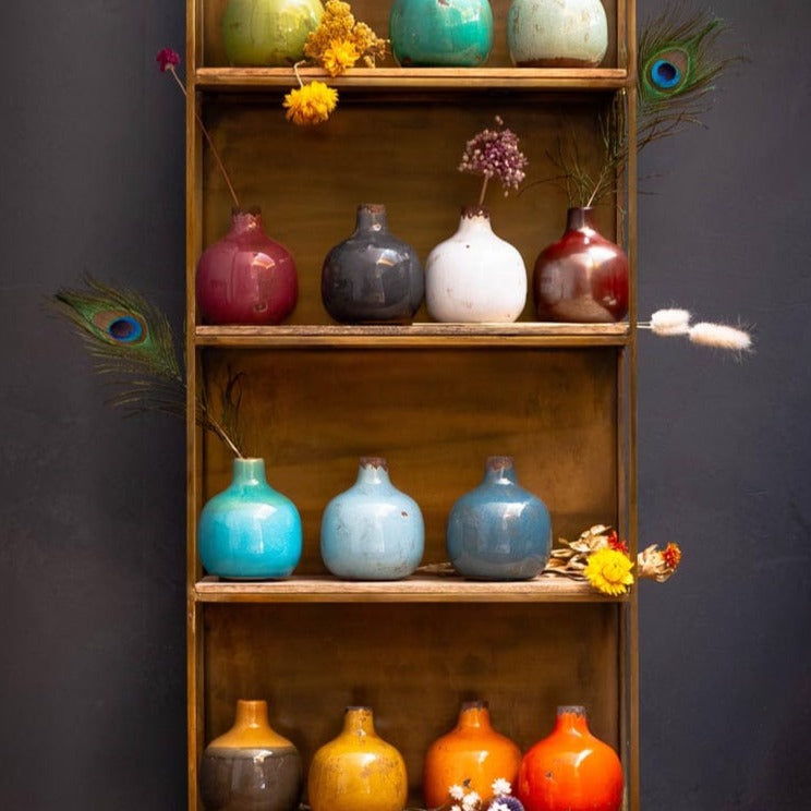 Étagère en bois sur laquelle sont posées des vases céramique colorés.
