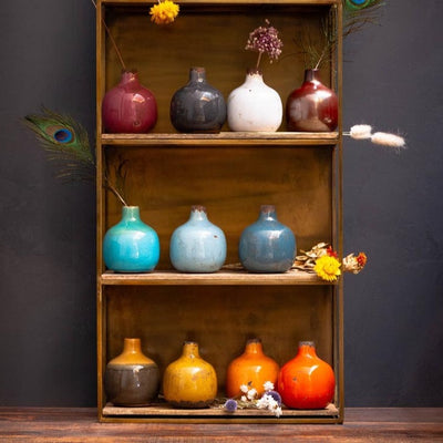 Étagère en bois sur laquelle sont posés des vases céramique de couleur.