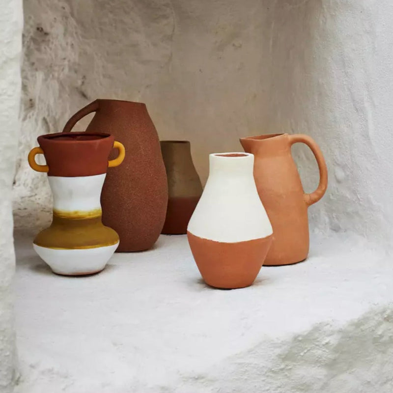 Vase en terre cuite blanc et terracotta dans une ambiance grès et pierre avec des vases en terracotta à l&