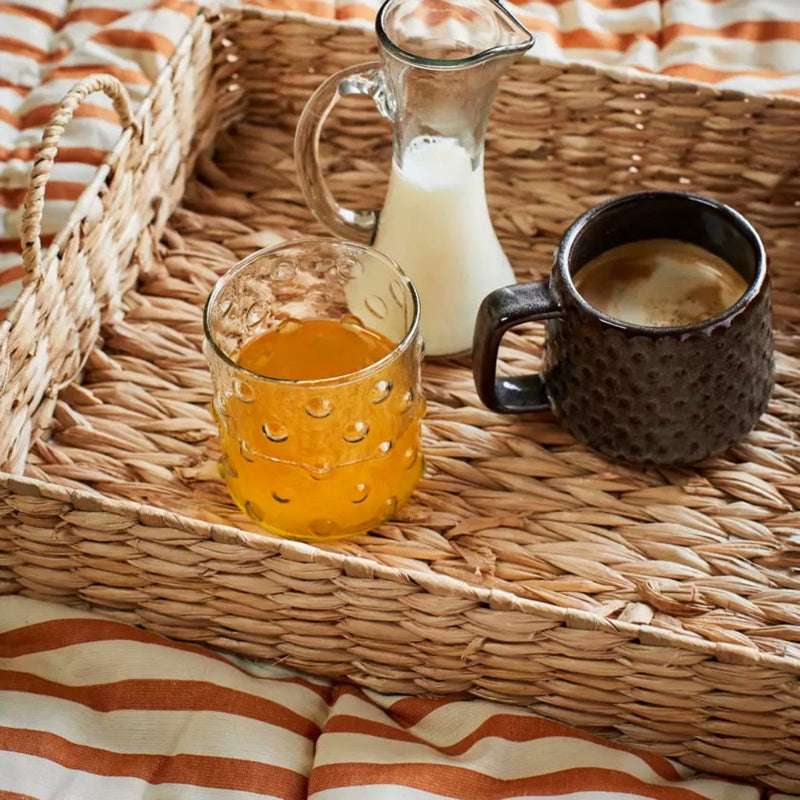 Verre transparent à points sur un plateau en raphia avec du jus d&